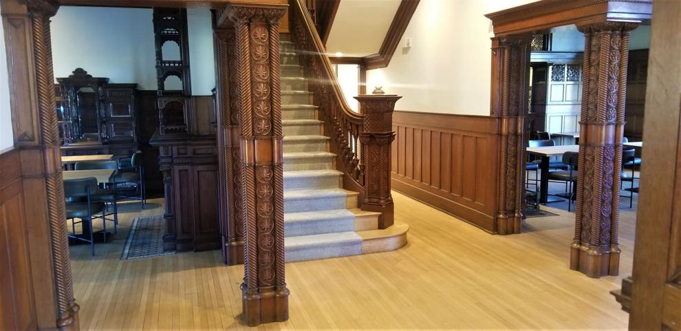 The grand staircase and intricately carved wooden columns inside The Wilbur Mansion, showcasing its restored historic interior and elegant craftsmanship.